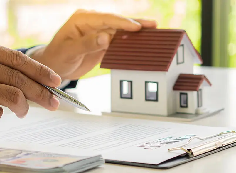 OurServices_LP-converted hands touching a small model of a house while pointing at paperwork with a pen